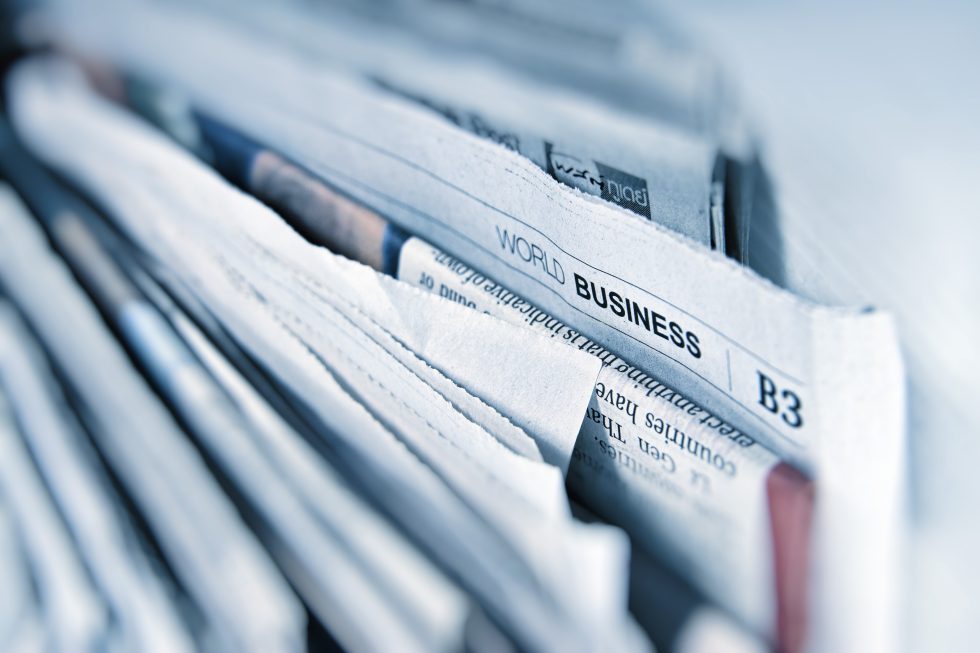 A close-up of stacked newspapers with a visible section labelled "World Business" and the section code "B3" at the top.