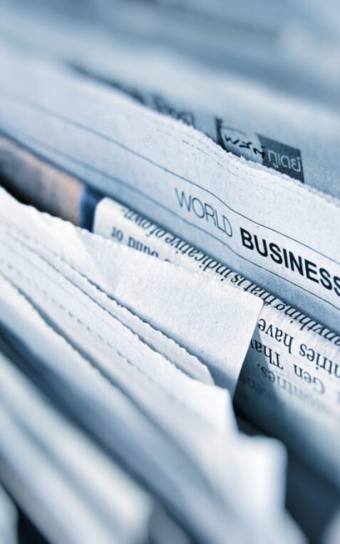 A close-up of stacked newspapers with a visible section labelled "World Business" and the section code "B3" at the top.