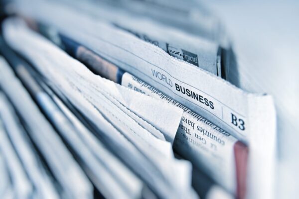 A close-up of stacked newspapers with a visible section labelled "World Business" and the section code "B3" at the top.
